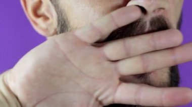 Sakallı genç bir adam yüzünde kırmızı rujla elini ovuşturuyor. Sakallı bir adam dudaklarına kırmızı ruj sürer, gülümser ve dudaklarına şaplak atar..