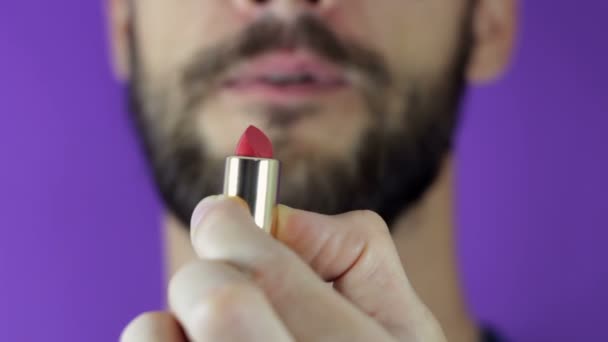 A young guy with a beard looks at the red lipstick and smiles.Close-up of a bearded man. He examines a bright red lipstick.A bearded man takes out lipstick, looks at her and smiles. — Stock Video