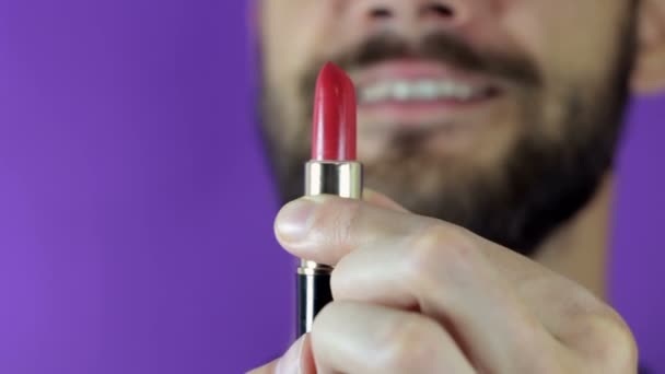 A young guy with a beard looks at the red lipstick and smiles.Close-up of a bearded man. He examines a bright red lipstick.A bearded man takes out lipstick, looks at her and smiles. — Stock Video
