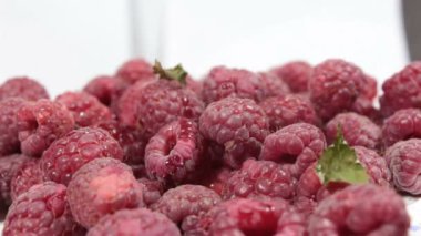 Güzel kadın elleri olgun sulu ahududuları bir tabaktan alır. Elleri yakın plan, olgun ahududuları tabaktan alıyor..