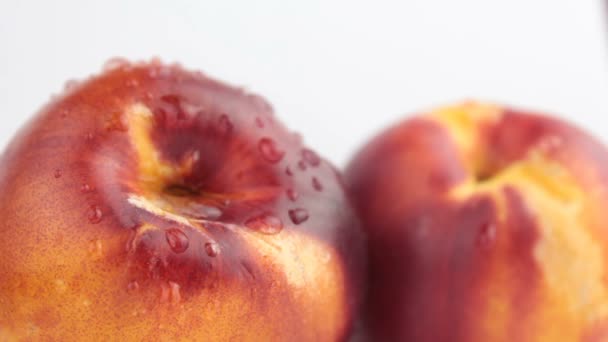 A drop of water flows down a fresh juicy peach. Fresh organic Peach covered with dew drops. Fresh juicy peaches on a white plate. — Stock Video