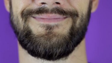 Yakışıklı sakallı adam kameraya bakıyor ve gülümsüyor. Gülümseyen sakallı bir gencin yakın çekimi..