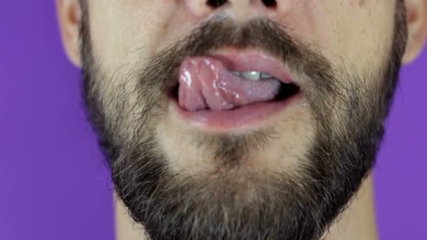 Close up portrait of a young bearded guy who is sexually licking his lips. Handsome bearded man looks at the camera and shows his tongue. — Stock Video