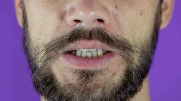 Close-up portrait of a young bearded guy who puts his finger to his mouth calling for silence. — Stock Video