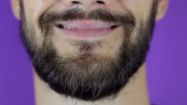 Jóképű szakállas férfi a kamerába néz és mosolyog. Közelkép egy mosolygós, fiatal szakállas fickóról.. — Stock videók