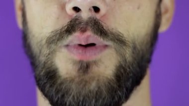 Ağzına mandal takan sakallı bir gencin yakın plan portresi..