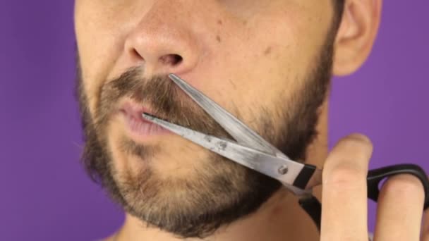 Guapo joven se corta la barba con tijeras . — Vídeos de Stock
