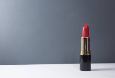 Masada kırmızı ruj var. Kırmızı parlak ruj yakın plan beyaz bir masada duruyor..