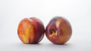 Beyaz tabakta taze şeftali. Beyaz bir tabakta taze organik şeftali nektarini. Masada kırmızı sarı şeftaliler yatıyor..