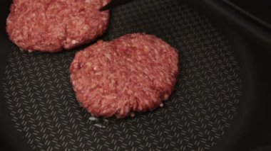 Şef kızartma tavasına köfte koyar. Sulu sığır pirzolası tavada kızartılır. Hamburger için sığır pirzolası..