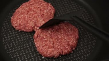 Şef kızartma tavasına köfte koyar. Sulu sığır pirzolası tavada kızartılır. Hamburger için sığır pirzolası..