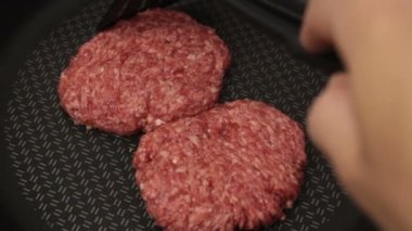 Şef kızartma tavasına köfte koyar. Sulu sığır pirzolası tavada kızartılır. Hamburger için sığır pirzolası..