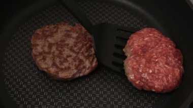 Şef kızartma tavasına köfte koyar. Sulu sığır pirzolası tavada kızartılır. Hamburger için sığır pirzolası..