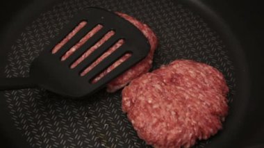 Bir şef ızgaraya köfte koyar. Tavada kızartılmış sulu bir sığır pirzolası. Biftek pirzolası ve ızgarada bir hamburger..