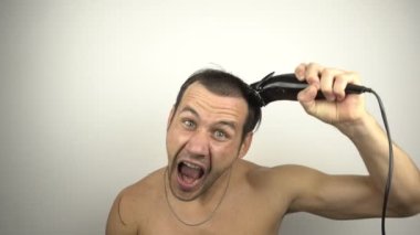 Adam kafasını tıraş eder ve aynaya bakarken yüksek sesle bağırır. Aynanın önünde genç ve komik bir adam evde karantinada otururken saçını saç makasıyla kesiyor..  