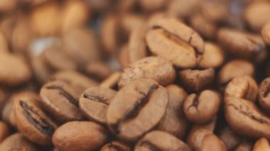 Kahve çekirdekleri dönüşümüne yakın çekim. Kavrulmuş aromatik kahve taneleri bir tabakta döner..