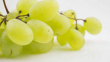 Olgun sulu üzümler bir tabakta döner. Bir demet beyaz üzümün yakın çekimi. Taze sulu üzümler beyaz arka planda döner.