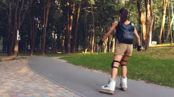 Tineri cuplu fericit rollerblading în parc ținându-se de mână. Tânăra fată atrăgătoare şi un tânăr care se plimbă prin parc. Cuplu tânăr îndrăgostit se bucură de patinaj cu role într-un parc de vară . — Videoclip de stoc