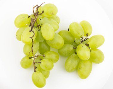 Olgun sulu üzümler bir tabakta döner. Bir demet beyaz üzümün yakın çekimi. Taze sulu üzümler beyaz arka planda döner.