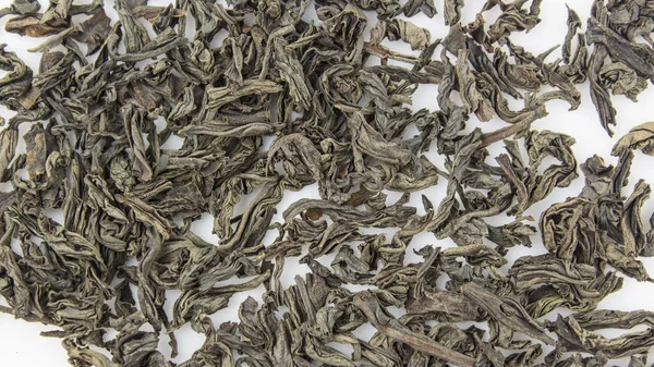 stock image A handful of large leaf black tea on a white plate. Close-up of large leaf black tea on a white background. Dried black tea leaves on a plate.