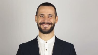 Genç başarılı iş adamı kameraya bakıyor ve gülümsüyor. Genç sakallı iş adamı geniş bir gülümsemeyle kameraya bakıyor. .