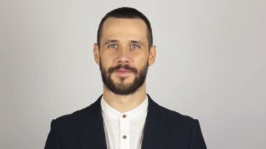 Genç başarılı iş adamı kameraya bakıyor ve gülümsüyor. Genç sakallı iş adamı geniş bir gülümsemeyle kameraya bakıyor. .