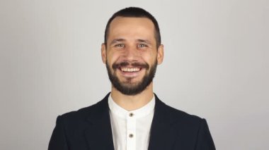 Genç başarılı iş adamı kameraya bakıyor ve gülümsüyor. Genç sakallı iş adamı geniş bir gülümsemeyle kameraya bakıyor. .