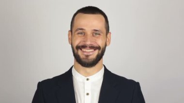 Genç başarılı iş adamı kameraya bakıyor ve gülümsüyor. Genç sakallı iş adamı geniş bir gülümsemeyle kameraya bakıyor. .