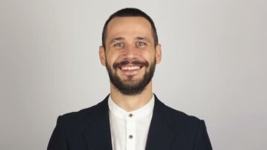 Genç başarılı iş adamı kameraya bakıyor ve gülümsüyor. Genç sakallı iş adamı geniş bir gülümsemeyle kameraya bakıyor. .