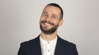 Mavi takım elbiseli genç yakışıklı bir işadamı kameraya bakıyor ve gülüyor..