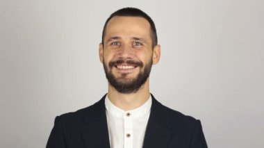 Mavi takım elbiseli genç yakışıklı bir işadamı kameraya bakıyor ve gülüyor..