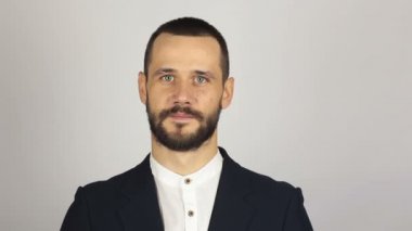 Mavi takım elbiseli genç ve güzel iş adamı gülümseyerek müşterileri selamlıyor. Genç başarılı iş adamı elini sallıyor, müşterileri selamlıyor..