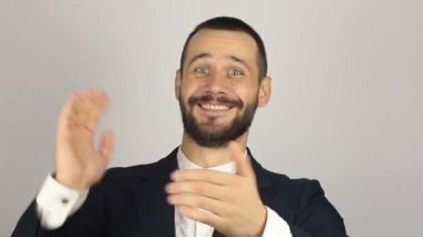 Yakışıklı genç işadamı gülümsüyor ve el çırpıyor, yeni müşterileri selamlıyor.