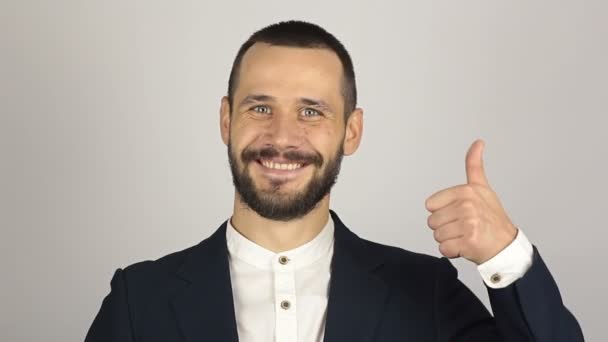 Joven hombre de negocios guapo está sonriendo y mostrando el pulgar hacia arriba con dos manos. — Vídeos de Stock