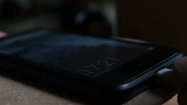 Akıllı telefonun şarj bataryasını kapat. Siyah akıllı telefon şarj cihazından şarj ediliyor..
