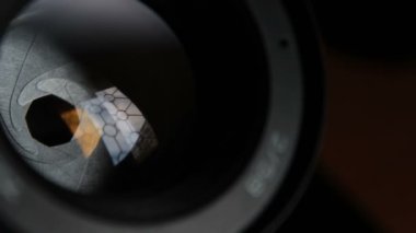 Kamera merceğindeki açıklık kanat hareketleri. Açık fotoğraf objektifi yakın plan. Kamera lensindeki pencerenin çok renkli yansımaları.