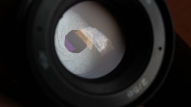 Kamera merceğindeki açıklık kanat hareketleri. Açık fotoğraf objektifi yakın plan. Kamera lensindeki pencerenin çok renkli yansımaları.