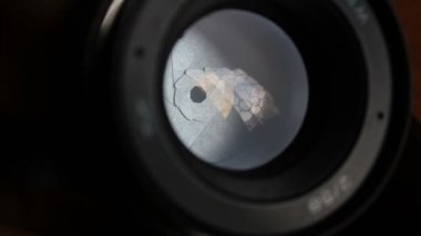 Kamera merceğindeki açıklık kanat hareketleri. Açık fotoğraf objektifi yakın plan. Kamera lensindeki pencerenin çok renkli yansımaları.