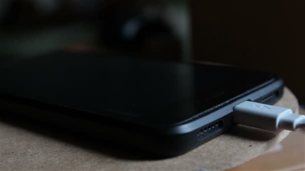 Zamknij ładowanie baterii smartfona. Czarny smartfon jest ładowany z ładowarki. — Wideo stockowe