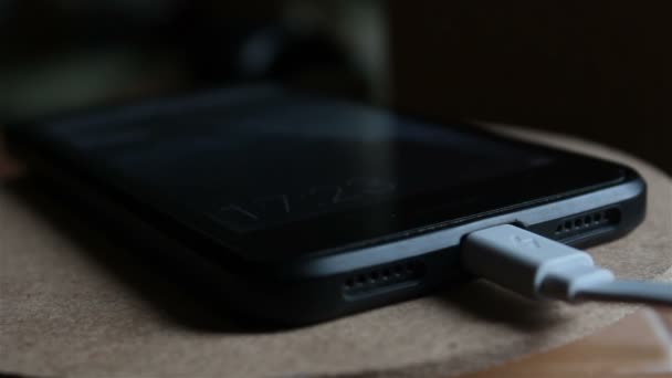 Sluiten van smartphone opladen batterij. Zwarte smartphone wordt opgeladen vanaf oplader. — Stockvideo