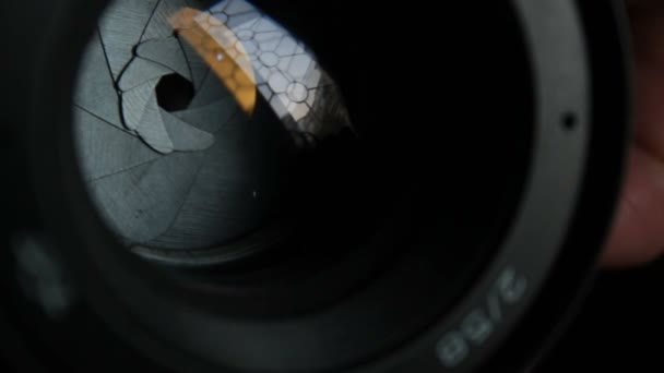 A movement of the aperture flaps on the camera lens. Aperture photo lens close-up. Multi-colored reflections of the window in the camera lens. — Stock Video
