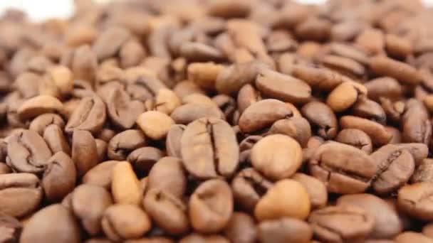 Închiderea rotației boabelor de cafea. Cerealele prăjite de cafea aromatică se rotesc pe o farfurie . — Videoclip de stoc