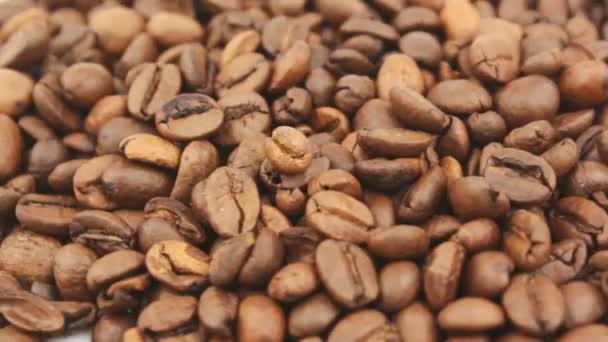 Los granos tostados de café aromático rotan en un plato. Primer plano de la rotación de granos de café. — Vídeo de stock