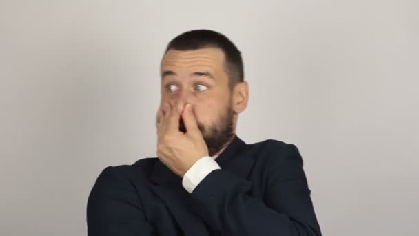 Een jonge knappe zakenman sluit zijn neus met zijn vingers voelt een slechte geur. — Stockvideo
