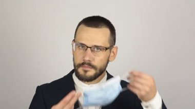 Genç ve başarılı bir iş adamı ortaklarıyla konuşurken tıbbi bir maske takar..