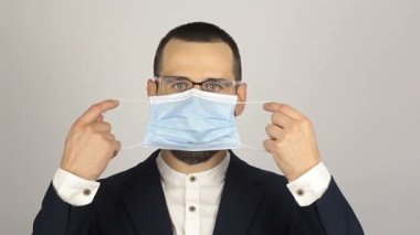 Genç ve başarılı bir iş adamı ortaklarıyla konuşurken tıbbi bir maske takar..