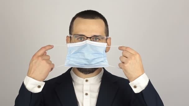 Młody, odnoszący sukcesy biznesmen zakłada medyczną maskę ochronną rozmawiając z partnerami. — Wideo stockowe