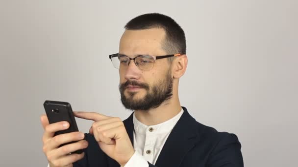 Joven hombre de negocios guapo está viendo una fuente de noticias en su teléfono inteligente. — Vídeo de stock