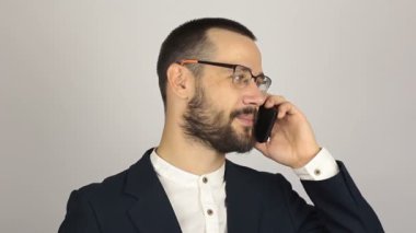 Genç ve başarılı bir iş adamı cep telefonuyla ortaklarıyla konuşuyor..