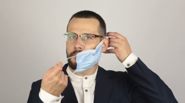 Genç ve başarılı bir iş adamı ortaklarıyla konuşurken tıbbi bir maske takar..